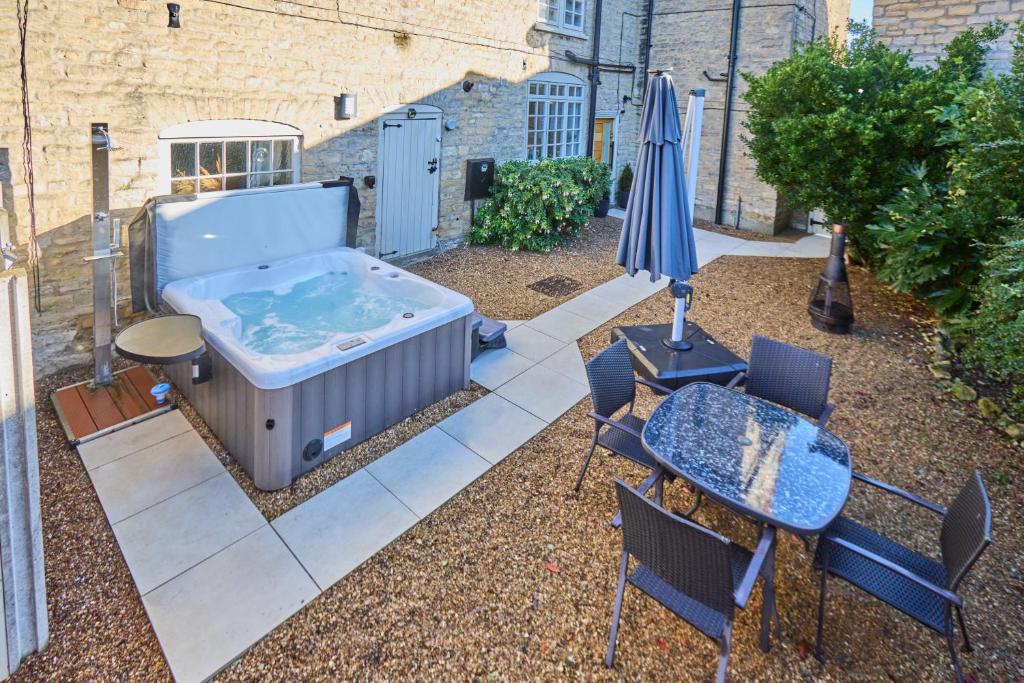 a patio with a hot tub and a table and an umbrella at The Retreat-luxury cottage with hot tub (sleeps 4) 