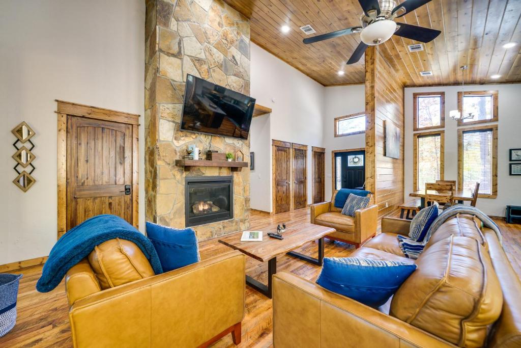 sala de estar con muebles de cuero y chimenea de piedra. en Broken Bow Family Cabin with Fireplace and Hot Tub! en Broken Bow