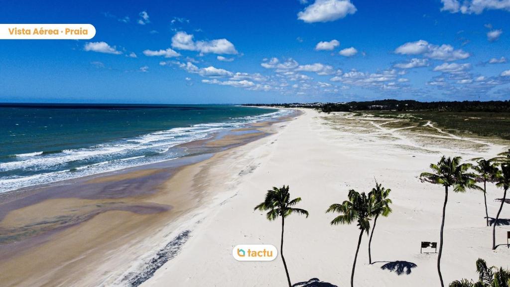 une vue sur une plage avec des palmiers et l'océan dans l'établissement Appartement compact à VG Sun Cumbuco par Tactu, à Paracumbuca
