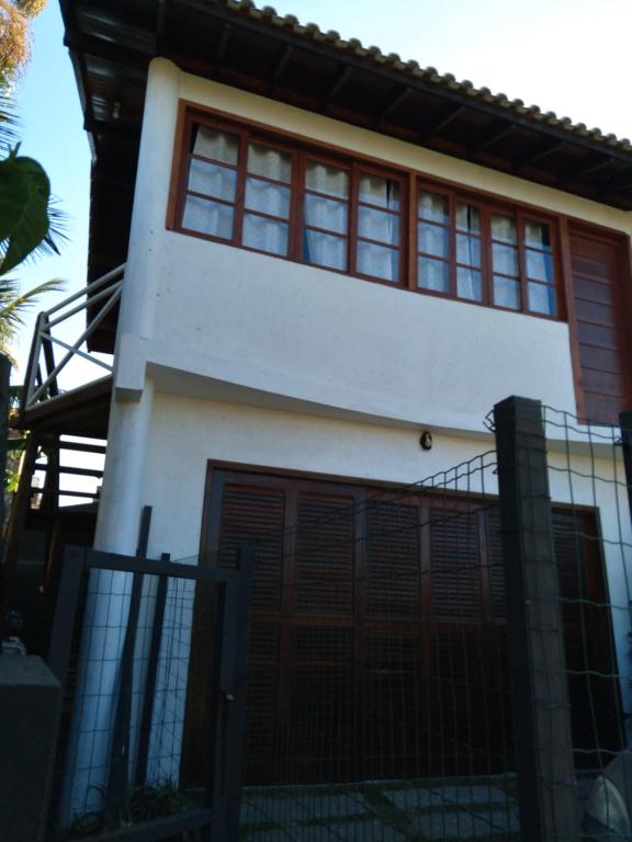 a white house with red windows and a fence at Apartamento na Barra de Ibiraquera in Imbituba