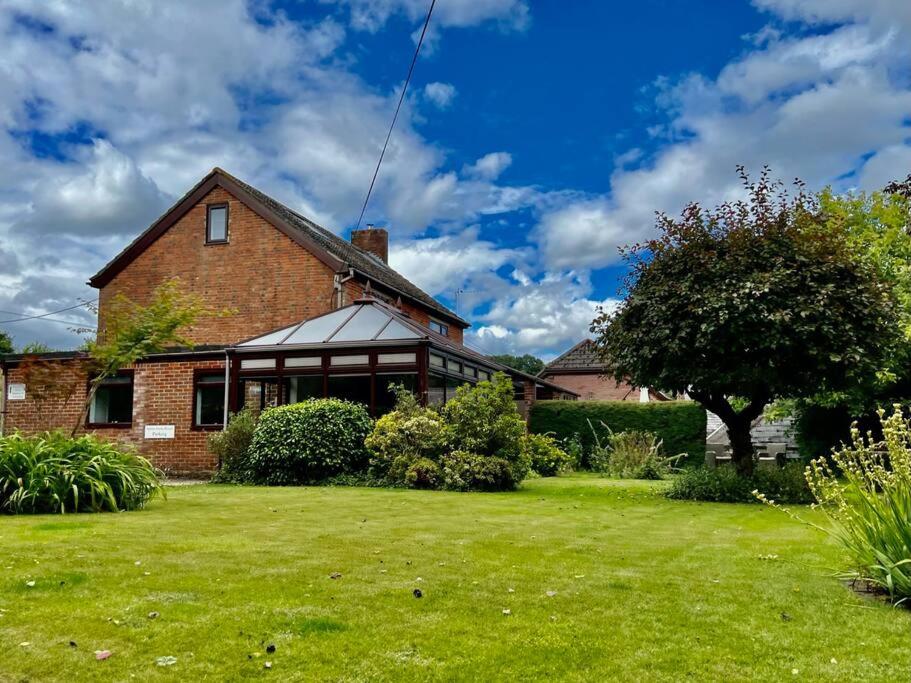 a brick house with a grass yard at Arniss Farmhouse in Fordingbridge