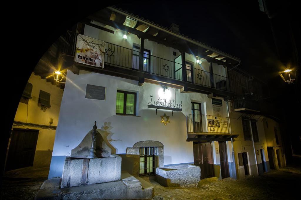 un edificio con una estatua delante de él por la noche en La Estrella de David, Apartamentos Rurales, en Hervás