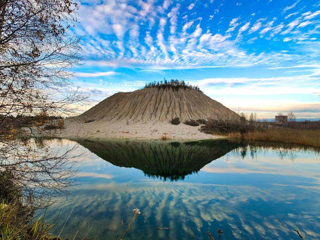 a hill with its reflection in the water at RUMMU Quarry Houses in Rummu