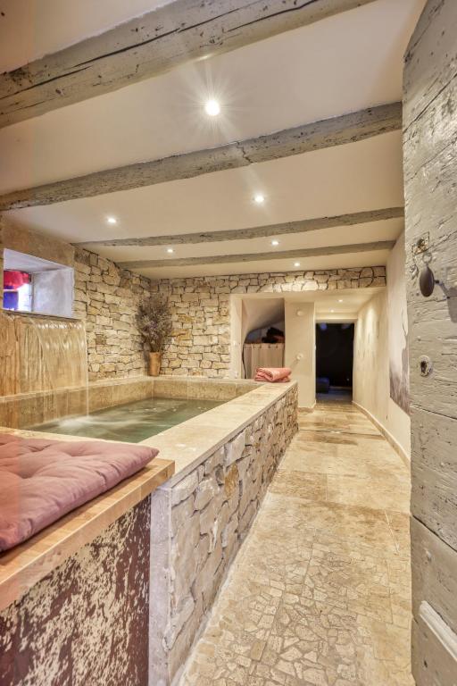 un bain à remous dans une pièce avec un mur en pierre dans l'établissement Les Jasmins en Provence, à LʼIsle-sur-la-Sorgue