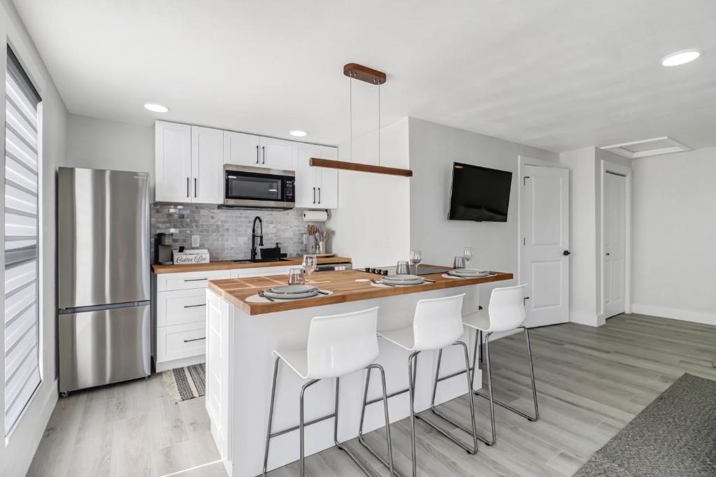 a kitchen with white cabinets and a bar with stools at Luxury Private Studio + Backyard in Naples