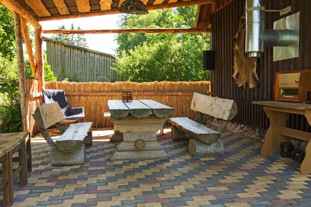 a patio with a table and chairs and a bench at Grāveri kempings in Usma