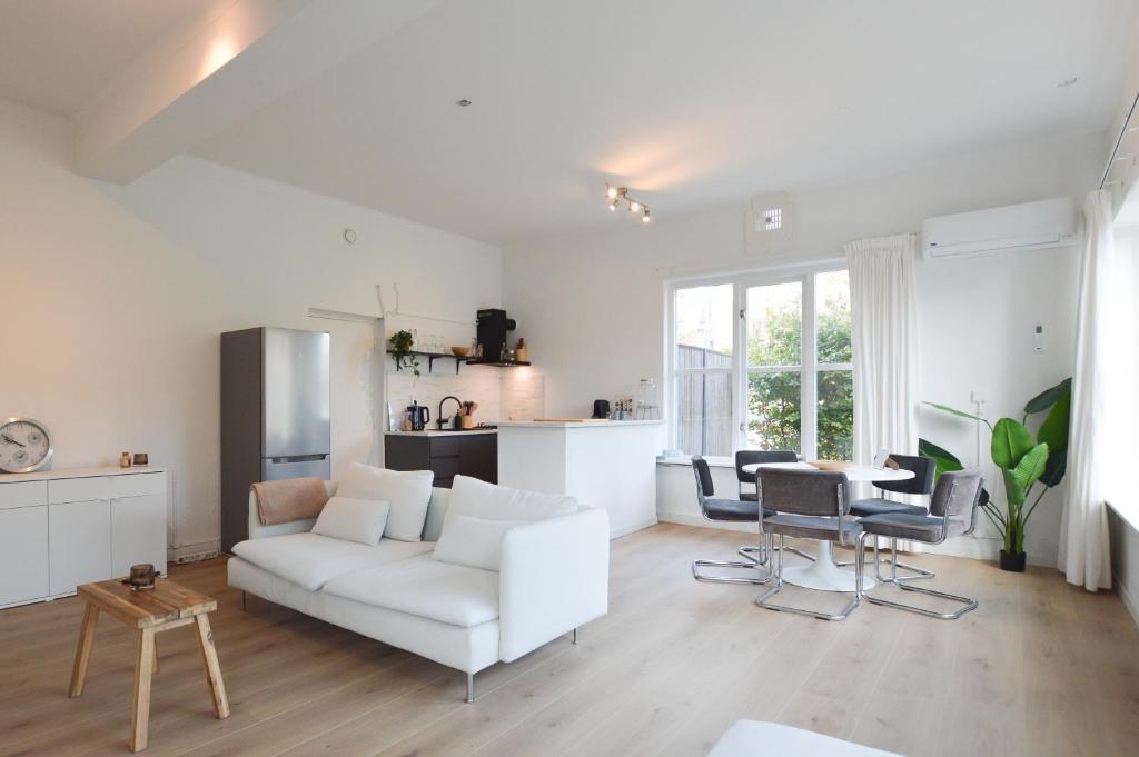 a white living room with a white couch and chairs at Boutique Appartement Oost in Nijmegen