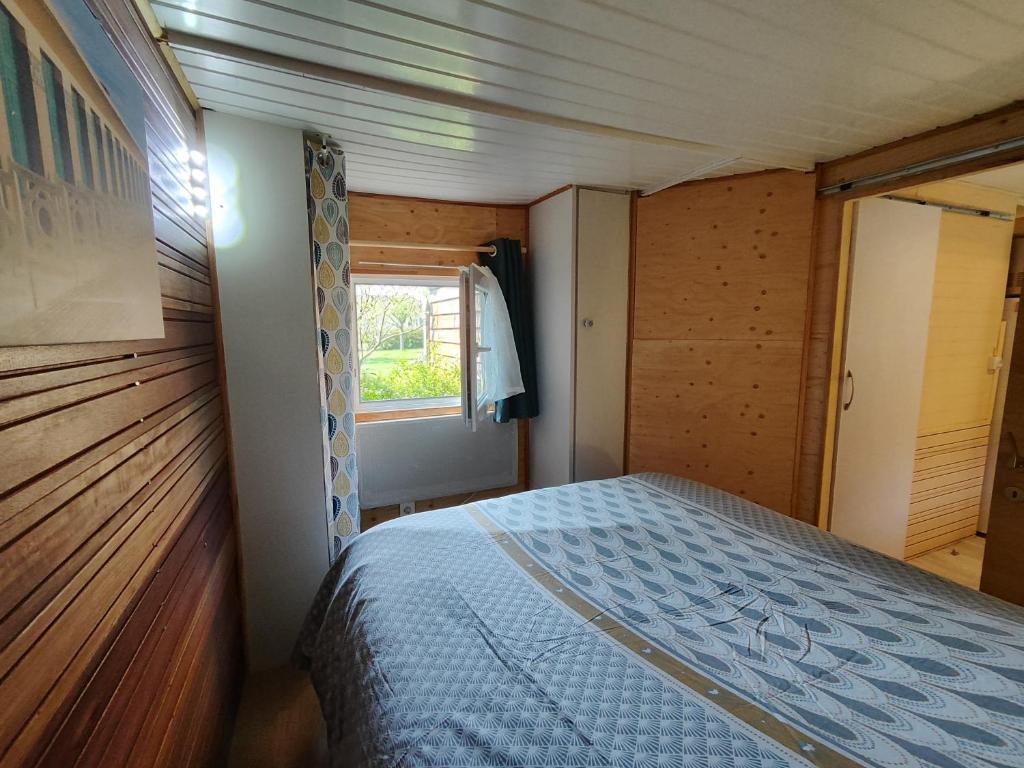 um quarto com uma cama num quarto com uma janela em Gite proche Côté fleurie em Martainville