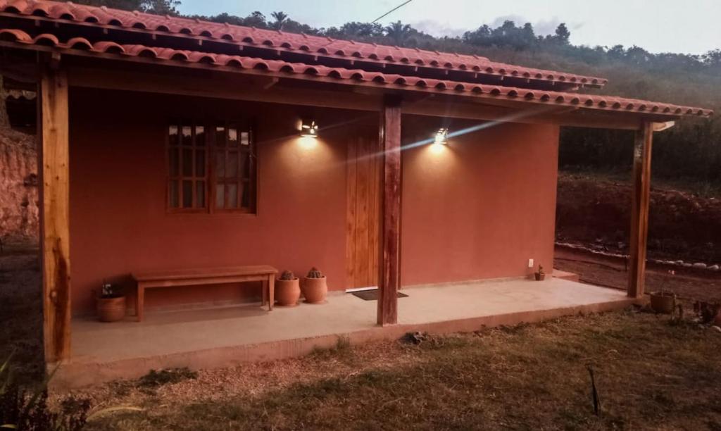 une petite maison avec un banc devant elle dans l'établissement Vila Sincorá - Chalé para 4 pessoas com cozinha a 2 km da portaria da Cachoeira do Buracão, à Ibicoara