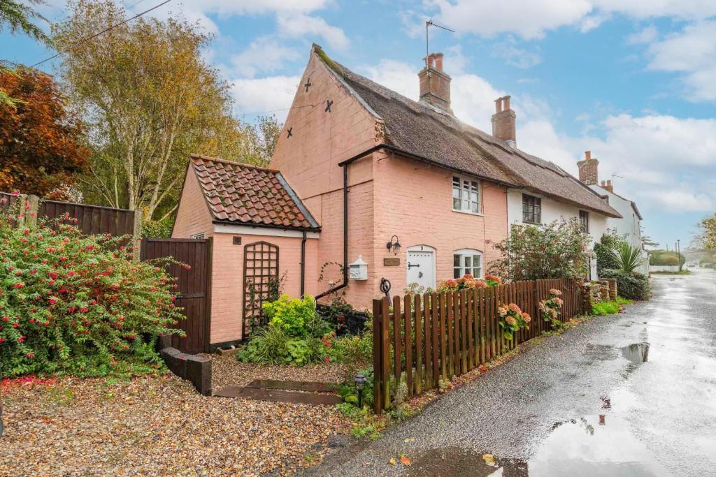 a pink house with a fence next to a driveway at Ships Timbers in Winterton-on-Sea