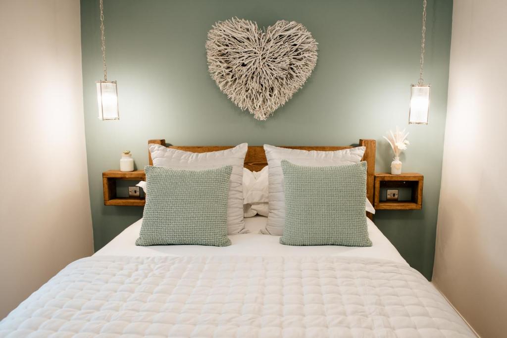 ein Schlafzimmer mit einem weißen Bett mit einem Herz an der Wand in der Unterkunft Otterburn House in Rothesay