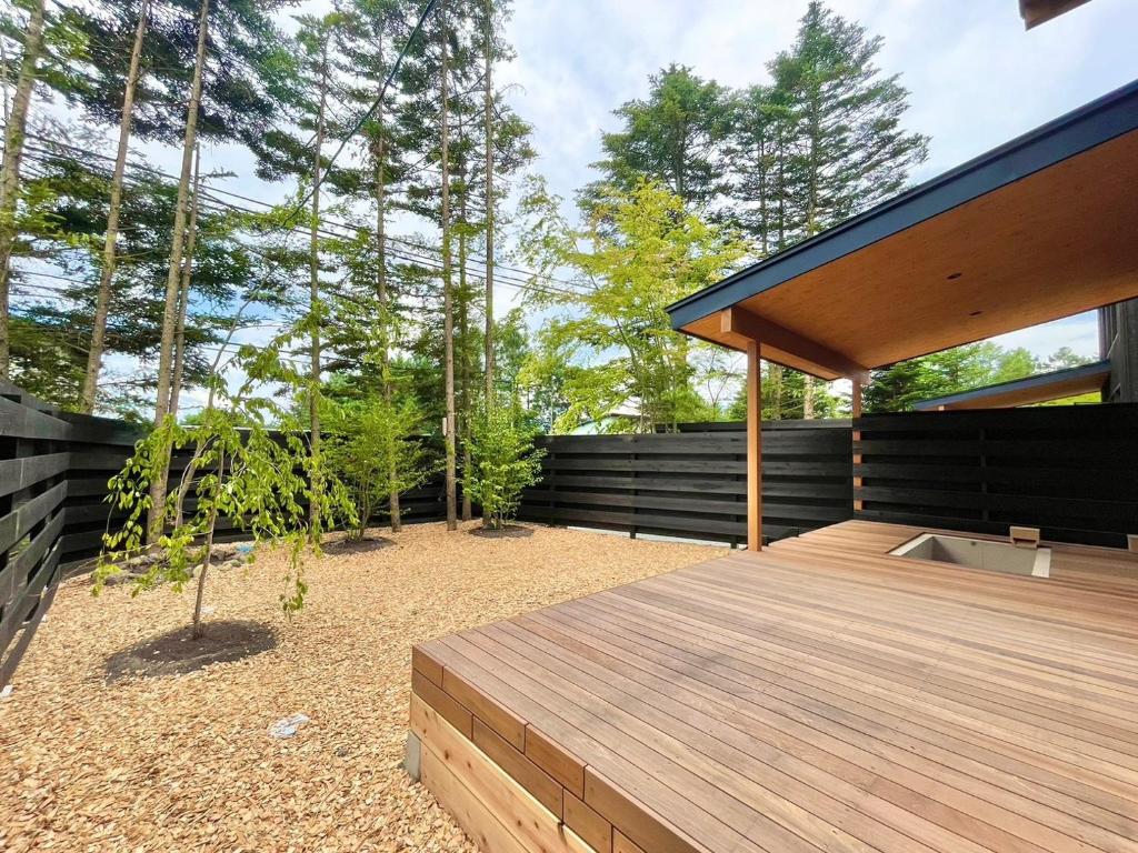 un cortile con una terrazza in legno e alcuni alberi di Karuizawa House Villa - Vacation STAY 16963v a Oiwake