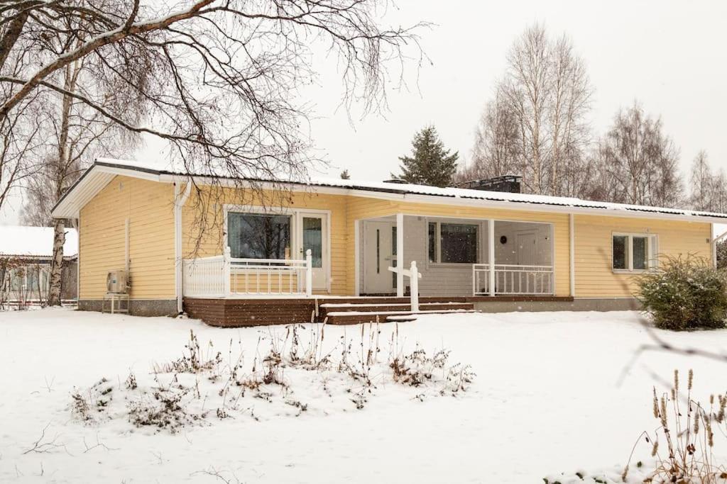 a yellow house with snow in front of it at Spacious house near santapark in Rovaniemi