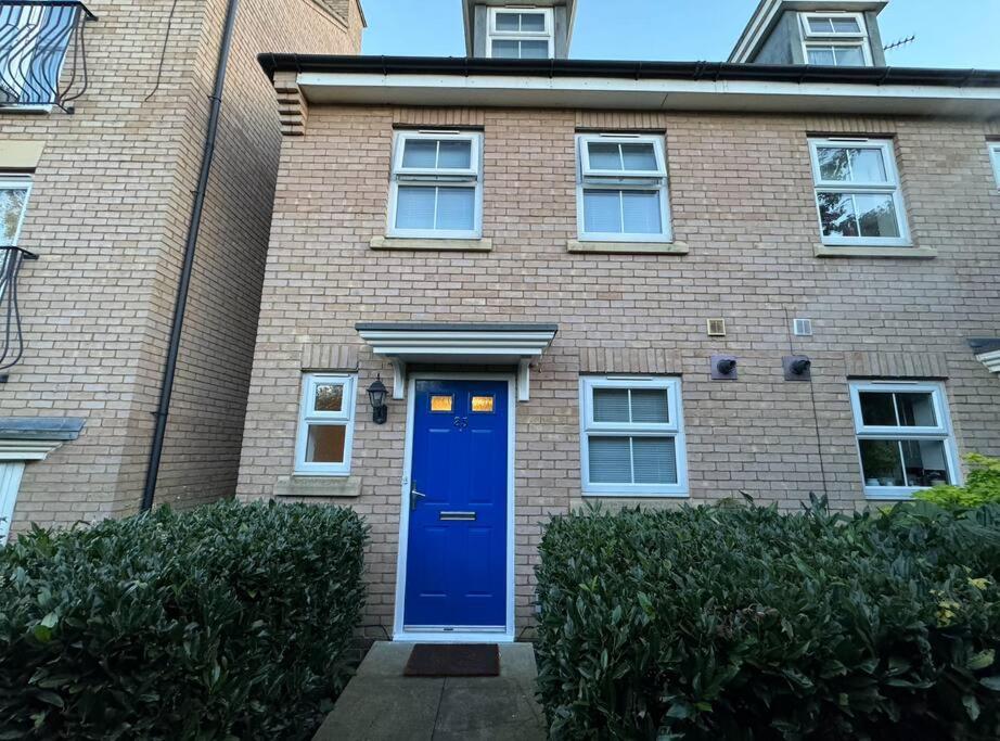 uma casa de tijolos com uma porta azul em frente em Modern TownHouse - 3 bed 2.5 bath 2 Private Gated Parking em Wellingborough