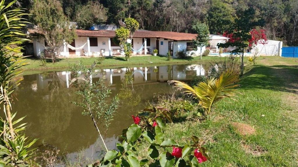 a house with a pond in front of it at Linda casa junto a natureza in Ibiúna