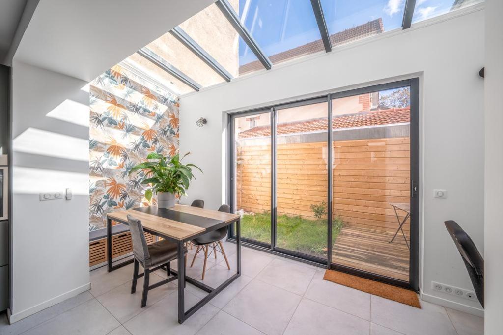 ein Esszimmer mit einem Tisch und einem großen Fenster in der Unterkunft Maison rénové proche Paris 15. in Malakoff