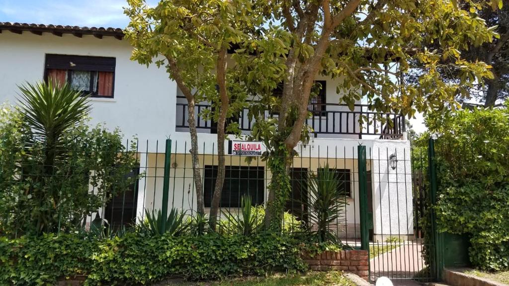 een wit huis met een hek en bomen bij La caracola in Villa Gesell