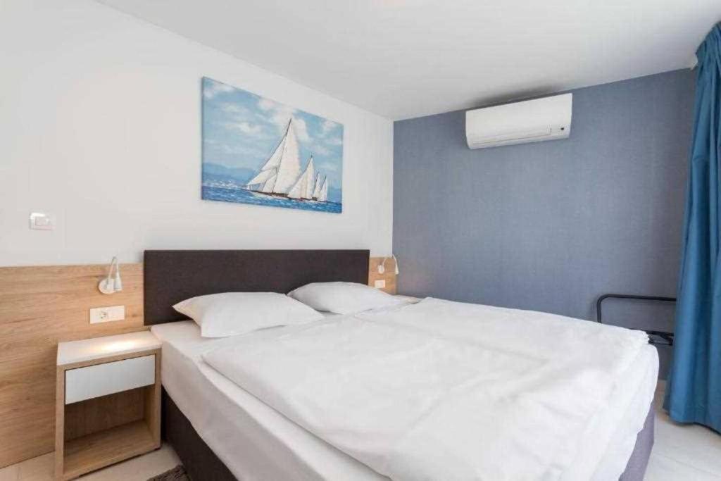 a bedroom with a white bed with a sailboat on the wall at LUX VISTA Suite in Umag