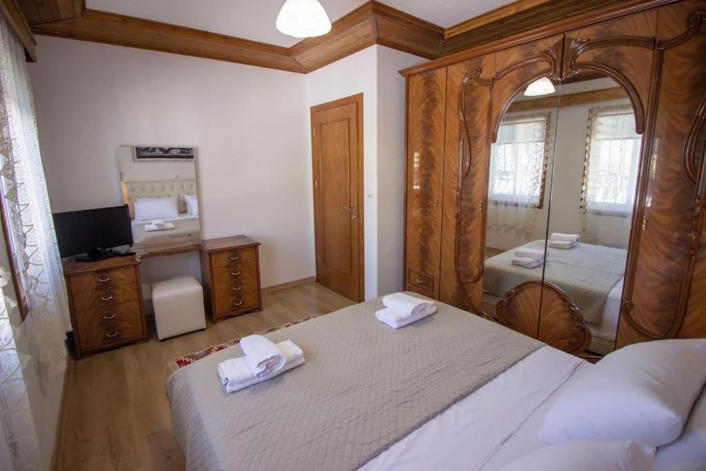 a bedroom with a large bed and a mirror at Emblematic House 3 in Gjirokastër