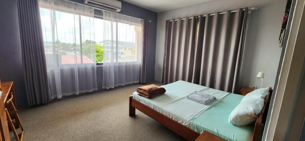 um quarto com uma cama e uma grande janela em Tropical Breeze Apartments em Paramaribo