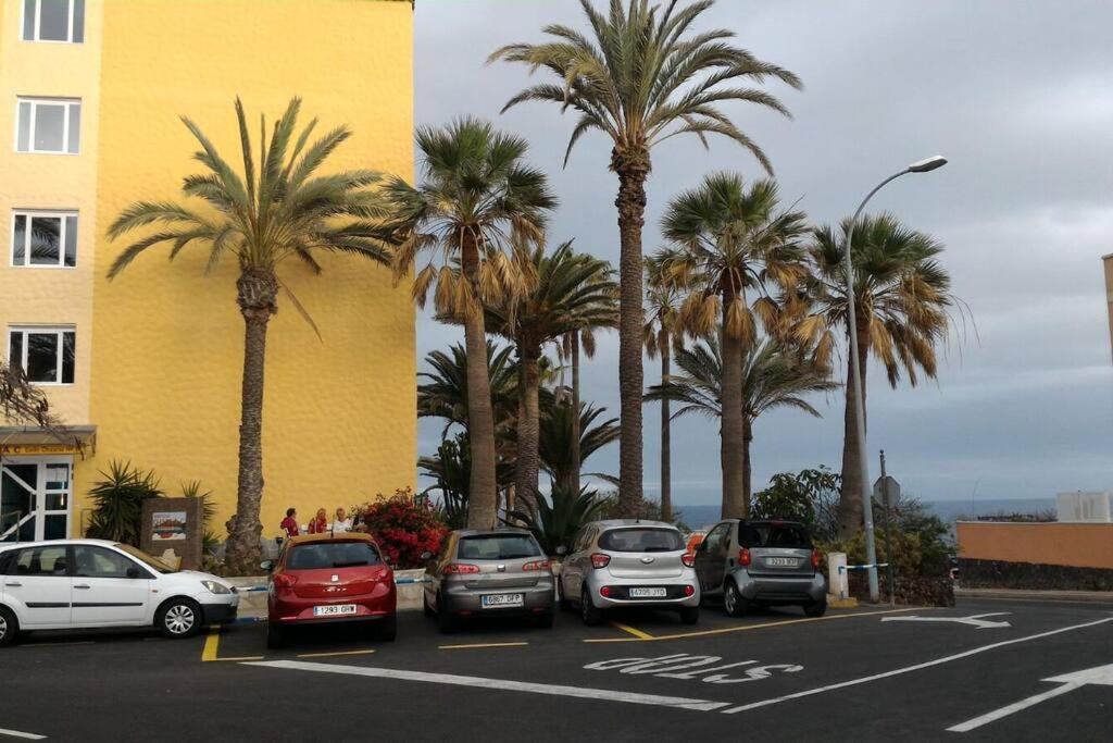 un aparcamiento con coches estacionados junto a palmeras en Tenerife Sur, en Arona