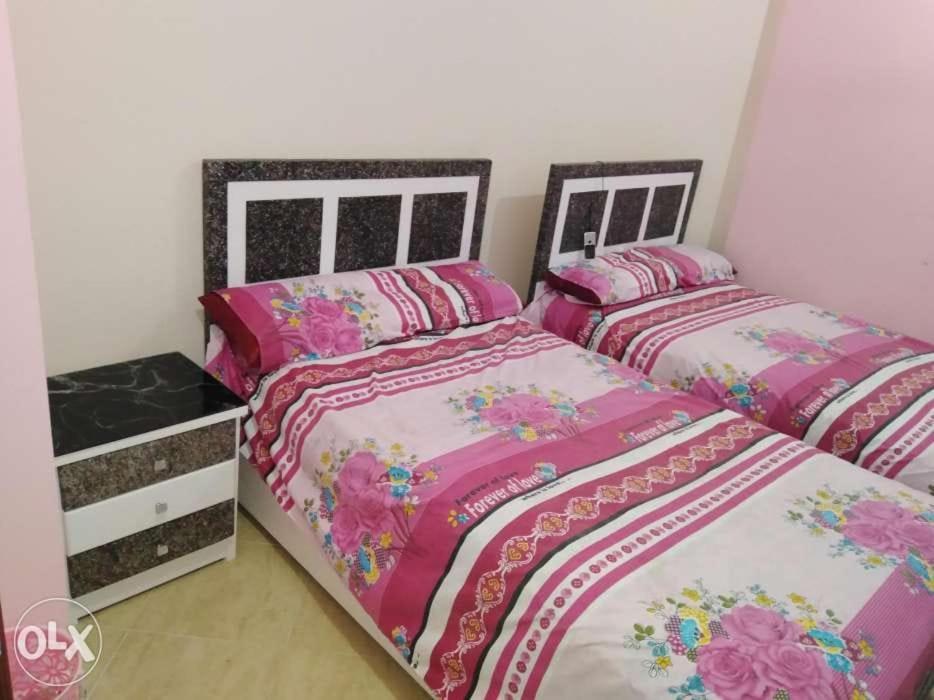 two beds in a bedroom with pink at كمبوند سيبريا in Hurghada