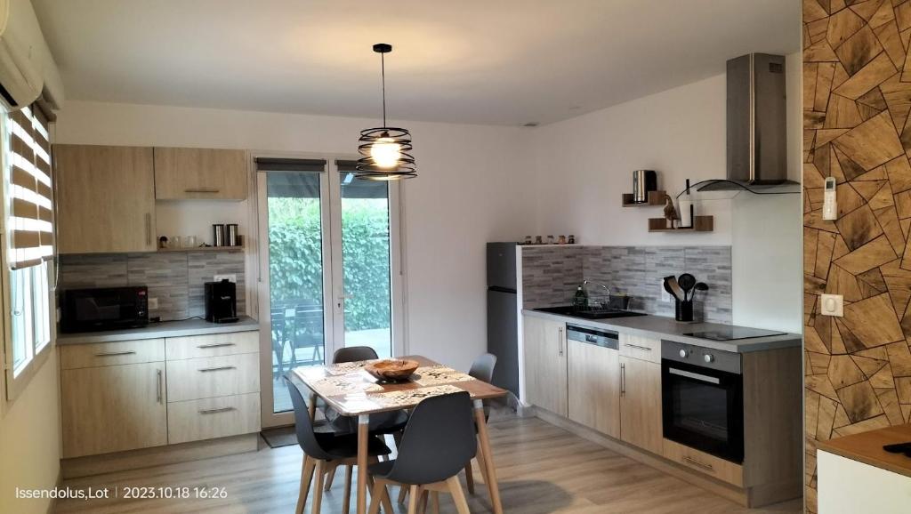 une cuisine avec une table et quelques chaises dans une pièce dans l'établissement Studio de jardin Le Cabanon avec SPA, à Issendolus