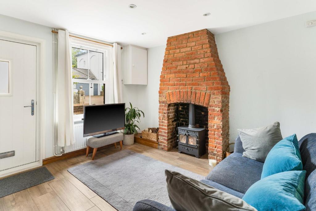 a living room with a couch and a brick fireplace at Little Braybrooke Cottage in Saffron Walden