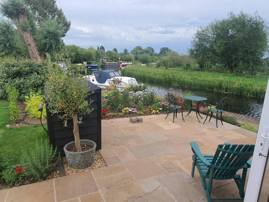 a patio with chairs and tables next to a river at River Cottage in Stoke Ferry