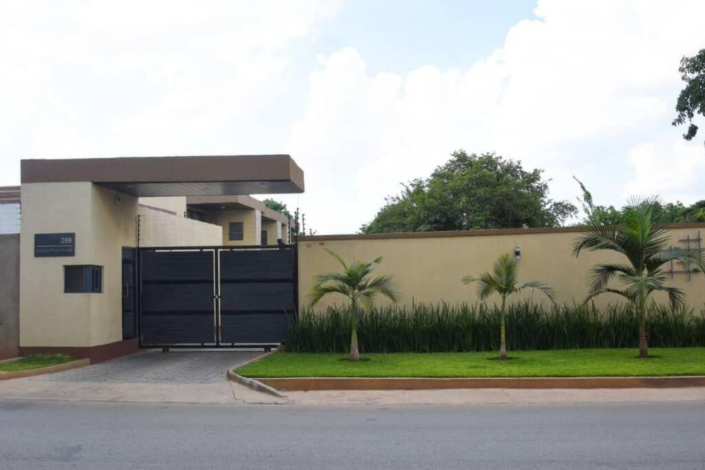 a building with a gate with palm trees in front of it at Dk Casa in Lusaka