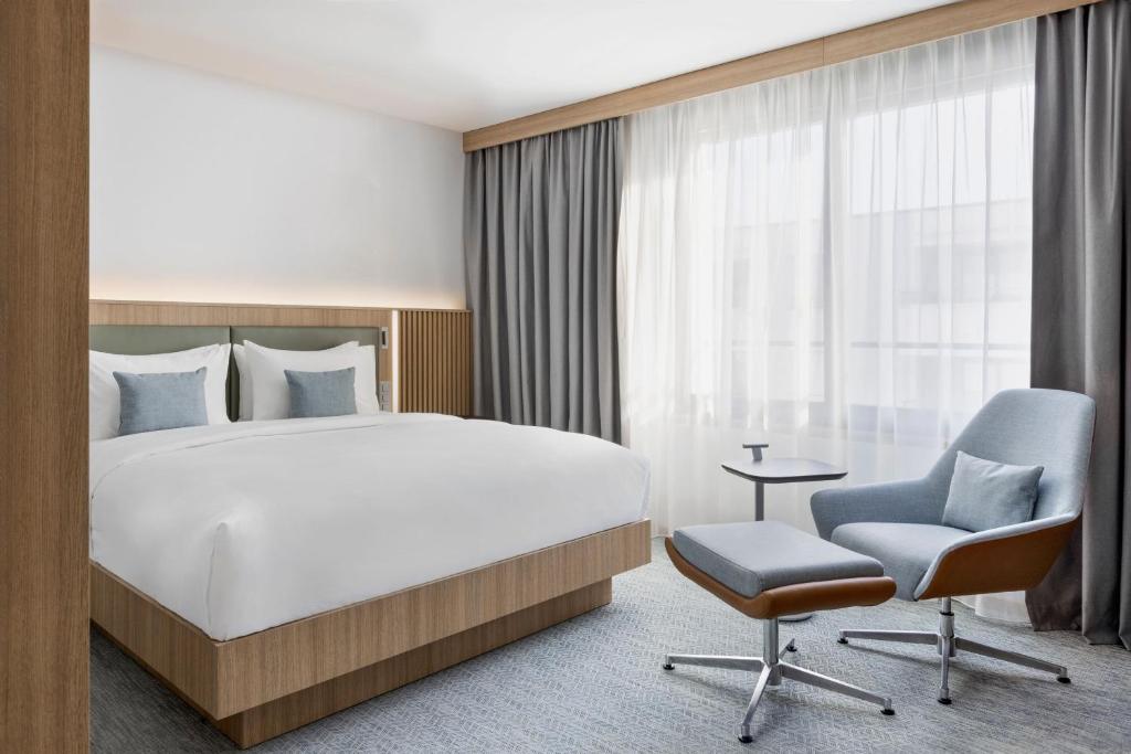 a hotel room with a bed and a chair at Courtyard by Marriott Biel Bienne in Biel