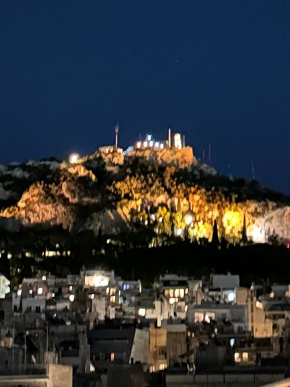 une ville au sommet d'une montagne la nuit dans l'établissement Neapolis apt lycabetus view, à Athènes