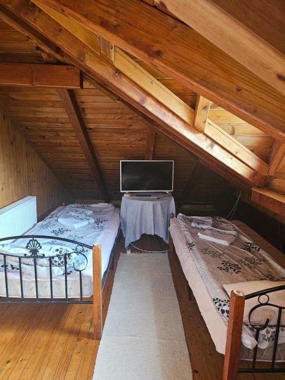 Novi GradにあるRestoran Domaćinのベッド2台とテレビが備わる屋根裏部屋です。