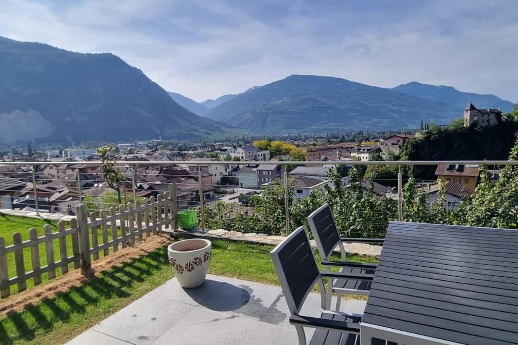 d'un balcon avec une table, des chaises et des montagnes. dans l'établissement Au Cœur du Vignoble Valaisan, à Saint-Léonard