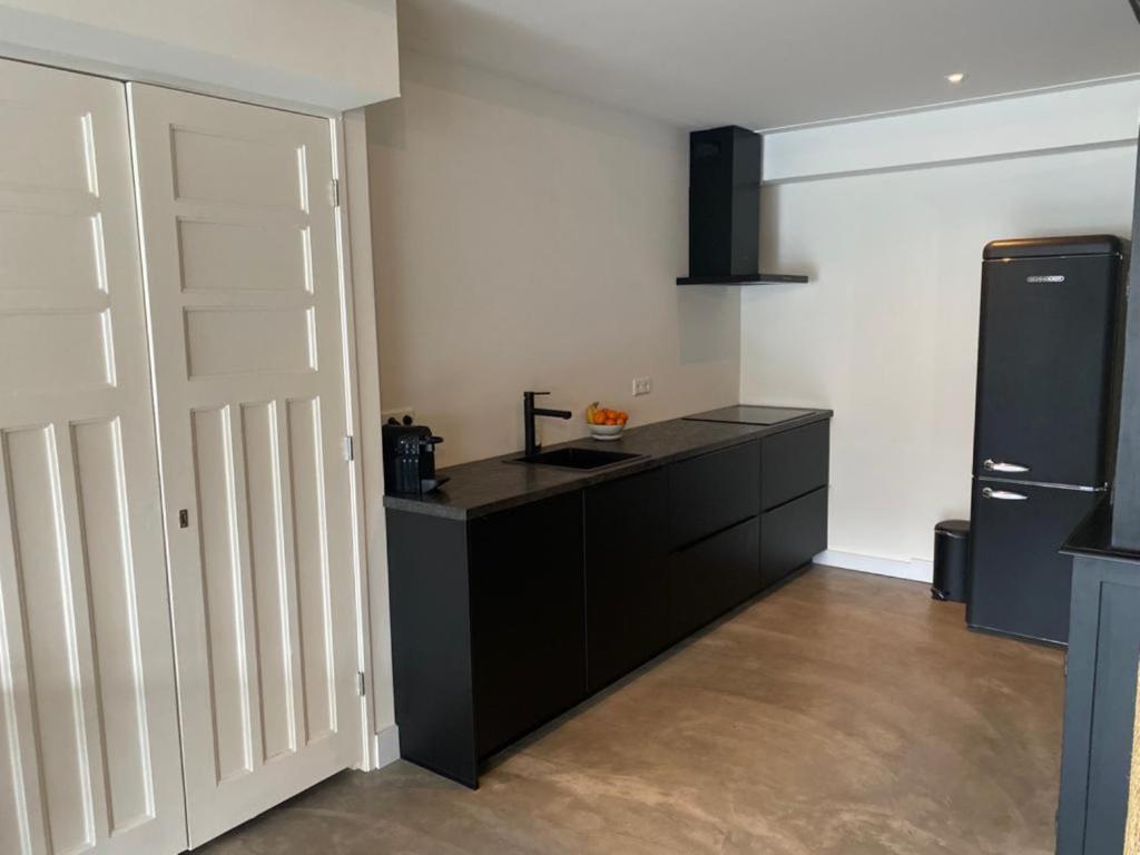 a kitchen with black cabinets and a black refrigerator at Stijlvol ruim studio-appartement nabij historisch centrum in Amersfoort