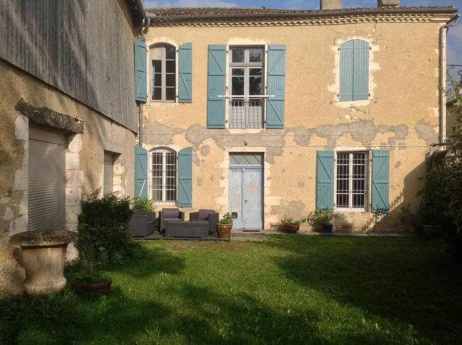 een groot huis met blauwe ramen en een tuin bij Ancien presbytere au coeur du village in Mauvezin