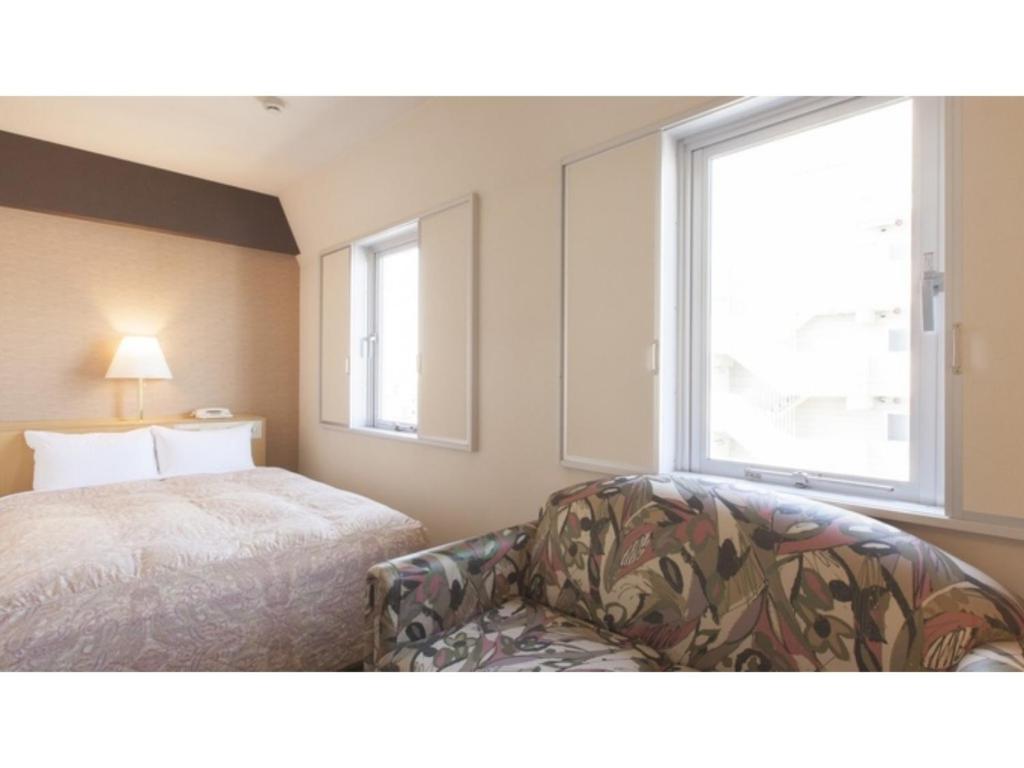 a bedroom with a bed and a chair and a window at Green Hotel Kitakami - Vacation STAY 09848v in Kitakami
