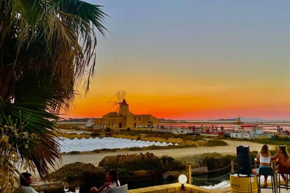 a sunset with a windmill in front of a building at Simarty Home in Marsala