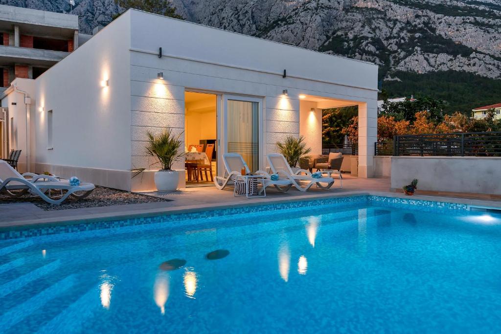 a villa with a swimming pool in front of a house at Family & Child friendly Villa Violet with Salt water pool in Makarska