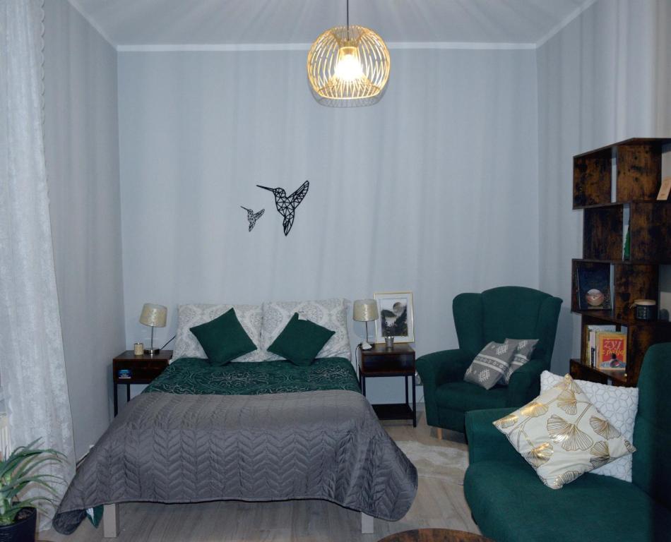 ein Schlafzimmer mit einem Bett und einem grünen Stuhl in der Unterkunft Apartament w Złotym Stoku Przystanek Las in Złoty Stok