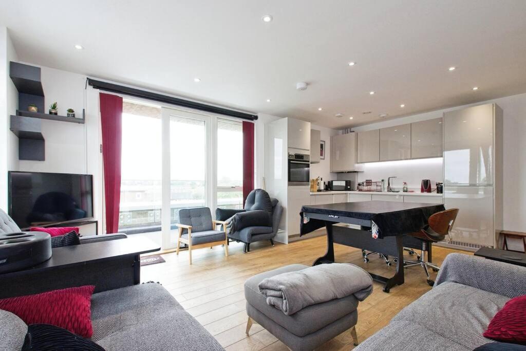 a living room with a grand piano and a kitchen at Greenwich O2 Apartment in London