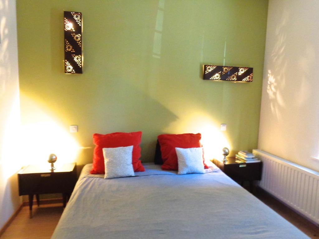 una camera da letto con un letto con cuscini rossi e bianchi di B&B La Chambre du Zodiaque a Bruxelles