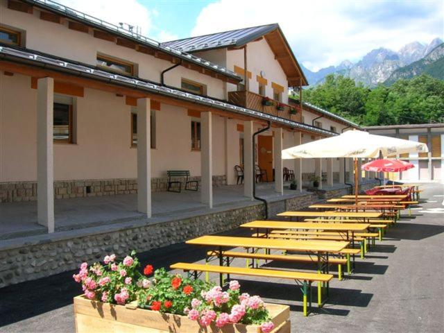 a row of wooden tables with umbrellas and flowers at Lunga Via Delle Dolomiti in Calalzo