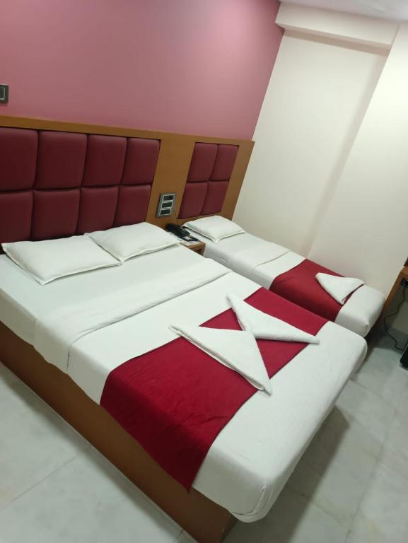 a bedroom with two beds with red and white sheets at Hotel airport annex in Mumbai