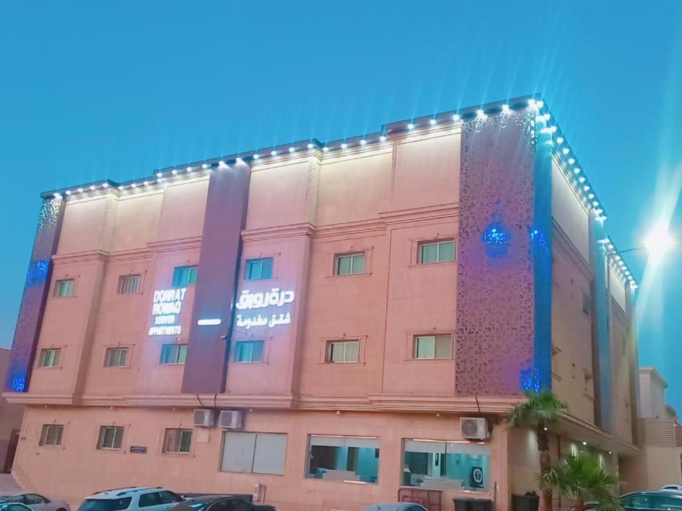 um edifício cor-de-rosa com luzes na lateral em درة رواق em Riyadh