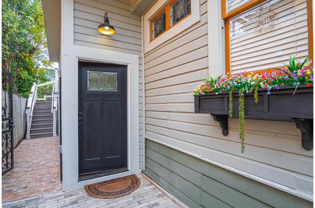 a black door on a house with flowers in a window at Exquisite Studio Guesthouse Near Downtowns Core in San Antonio