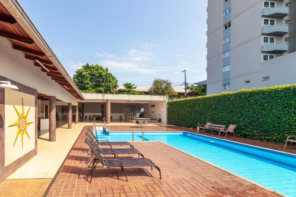 a swimming pool with lounge chairs next to a building at Luz Hotel by Castelo Itaipava in Foz do Iguaçu