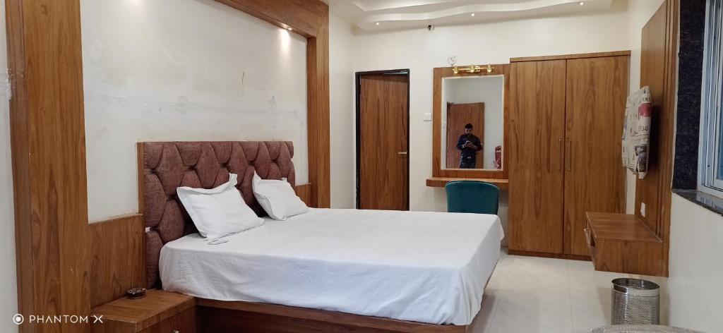 1 dormitorio con cama blanca y cabecero de madera en Rk Hotal en Pusad