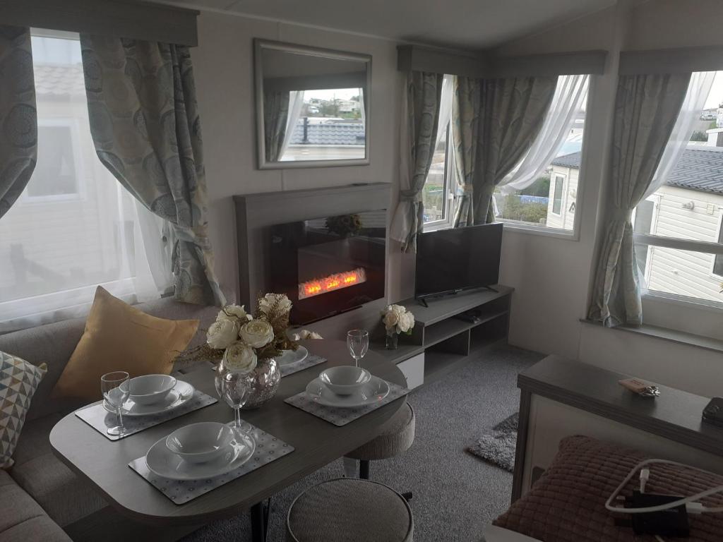 a living room with a table and a fireplace at Littlesea Haven Weymouth in Weymouth