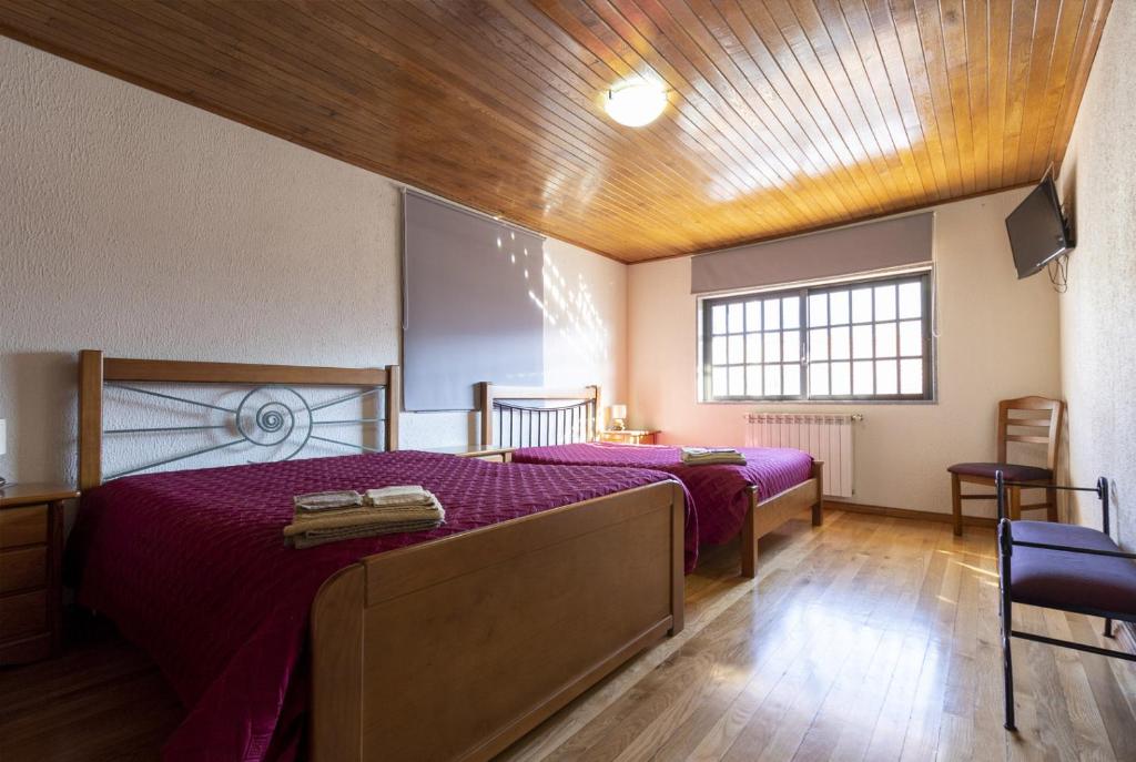 a bedroom with two beds with purple sheets and a wooden ceiling at Casa do Patrão - Quartos in Sabugueiro